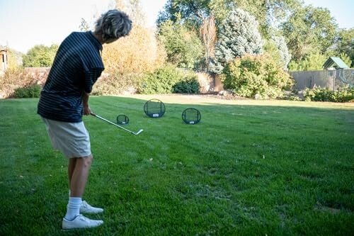 Person practicing golf in backyard with targets.