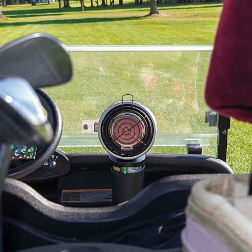 Portable heater inside a golf cart on a grassy field.