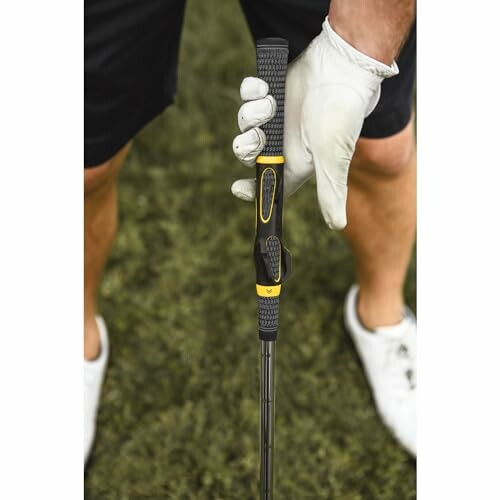 Golfer wearing glove holding a putter on grass