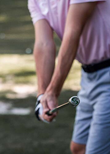 Golfer in pink shirt swinging a club on a golf course.