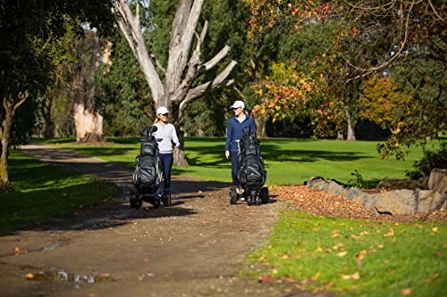 Two people walking with golf bags on a path in a park