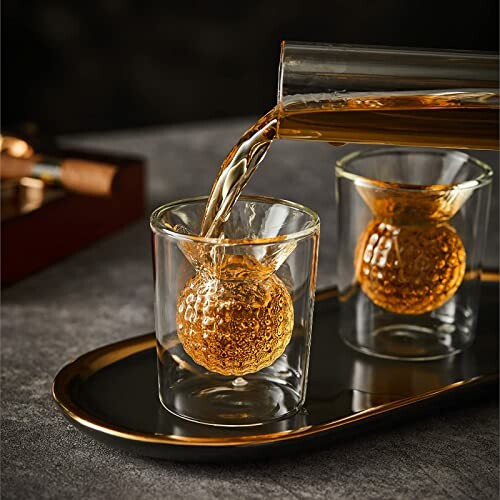 Whiskey being poured into a decorative glass on a tray.